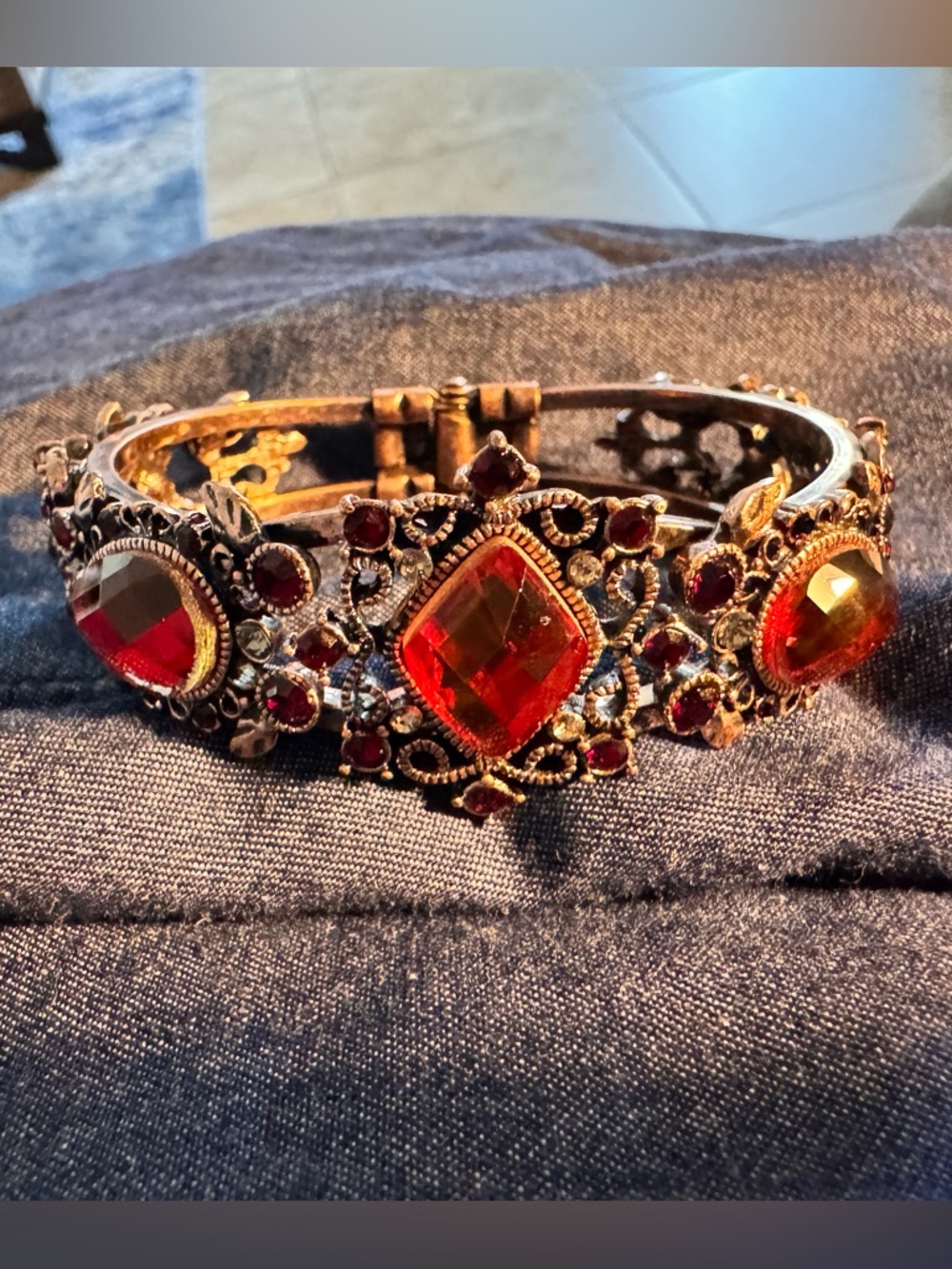 Vintage hinge-style bracelet featuring red  stones and ornate filigree metalwork